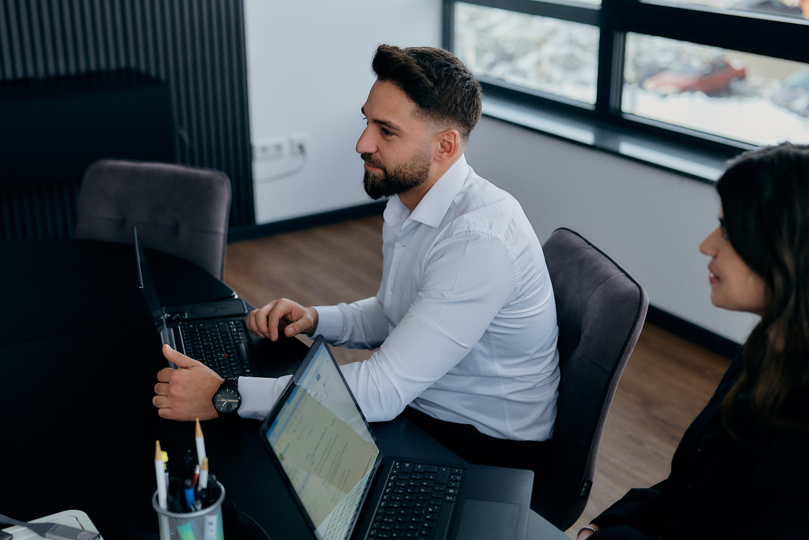 Zwei Mitarbeitende von MDSYSTEC arbeiten gemeinsam an Laptops in einer Büroumgebung